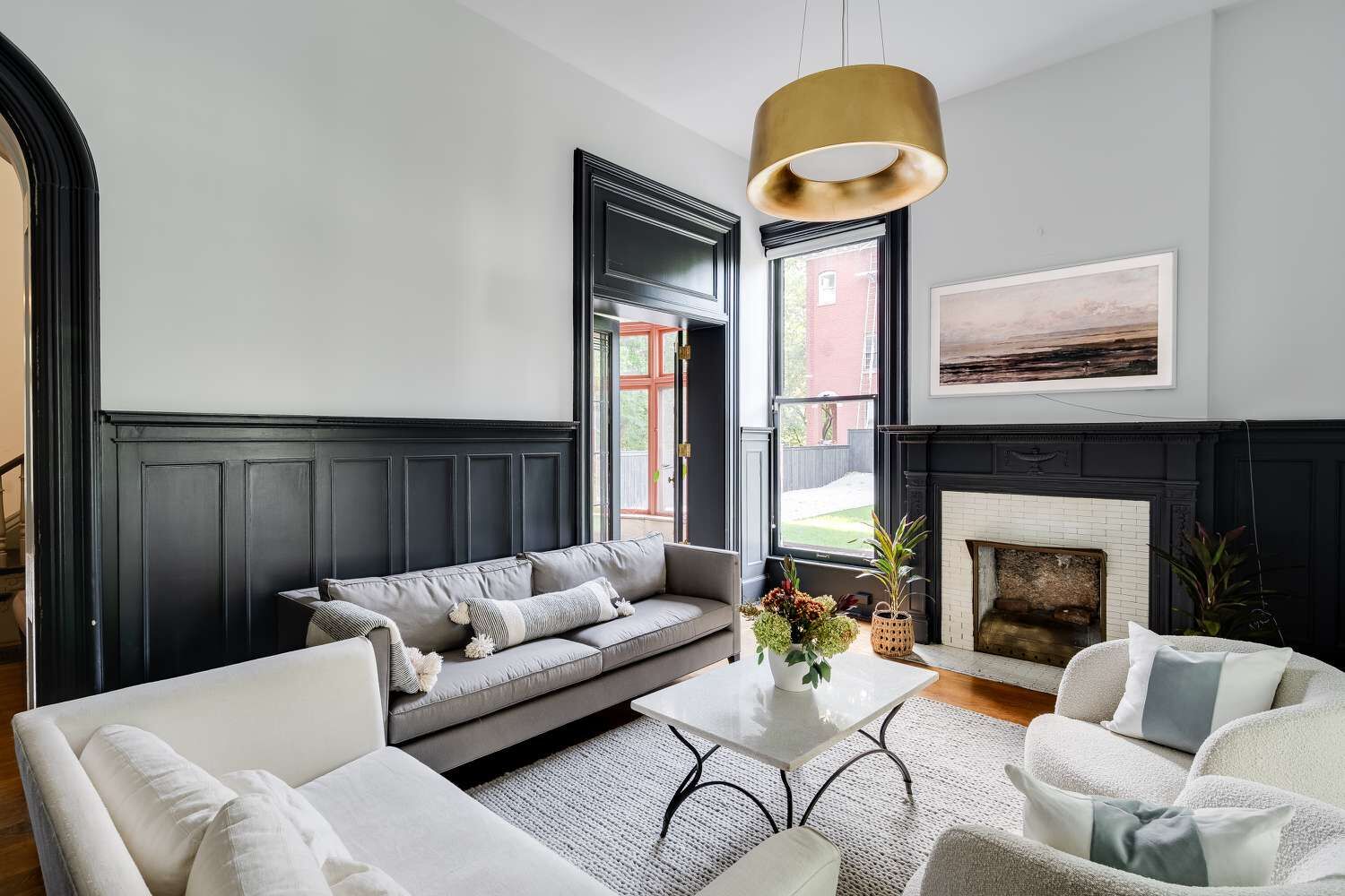 Living room with dark painted wainscotting and a marble fireplace